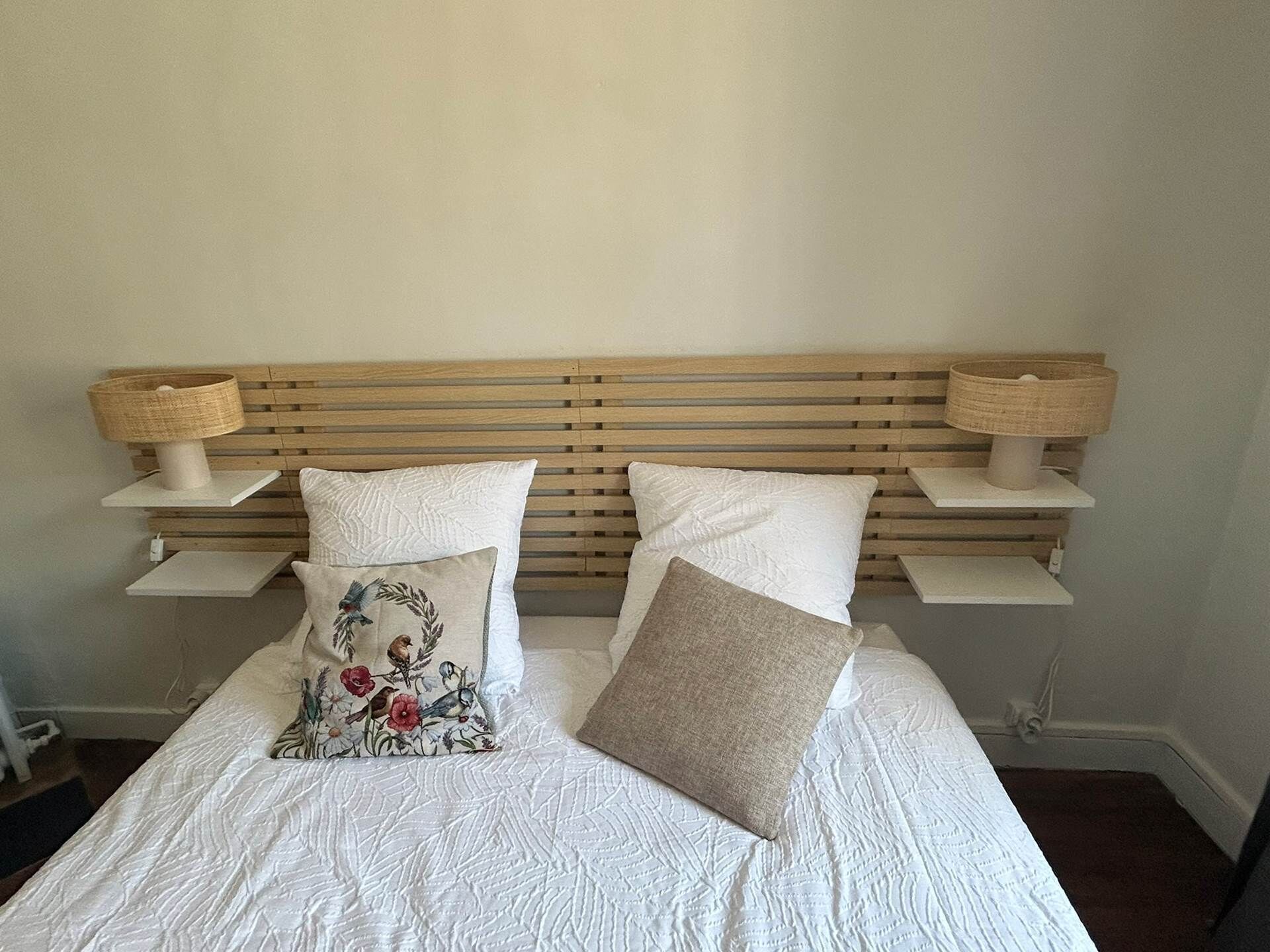 A bed with a wooden headboard, two bedside lamps, and two pillows.