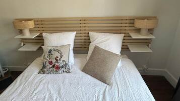 A bed with a wooden headboard, two bedside lamps, and two pillows.