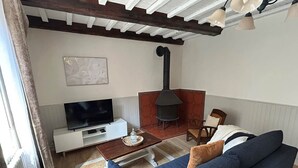 A cozy living room with a sofa, a TV, a fireplace, and a wooden table.