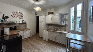 A modern kitchen with white cabinets, a wooden countertop, a hanging light fixture, and a window providing a view of the outside.