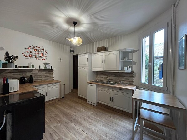 Una cocina moderna con armarios blancos, encimera de madera, lámpara colgante y ventana que ofrece vistas al exterior.