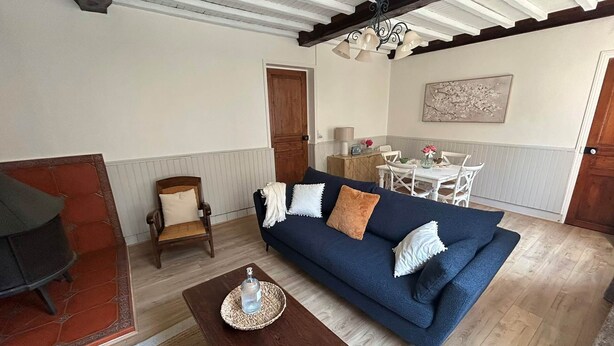 A living room with a blue sofa, wooden coffee table, and a dining area with a white table and chairs.