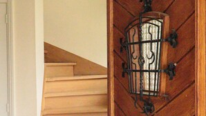 A wooden staircase with a decorative metal light fixture on the wall. - Villa Jasmin (Veyrier-du-Lac)