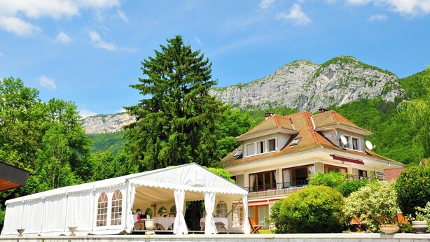 A large house with a balcony, surrounded by lush greenery and mountains in the background. - Villa Jasmin (Veyrier-du-Lac)