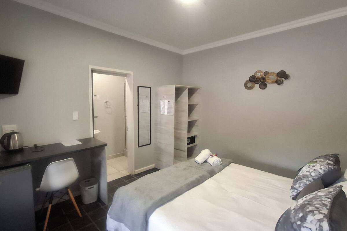 Ein Hotelzimmer mit Bett, Schreibtisch, Stuhl, Kleiderschrank und Fernseher.