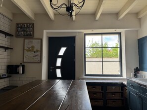 Eine Küche mit dunkler Holz Arbeitsplatte, einer schwarzen Tür mit Fenster und Blick auf Grünfläche draußen.