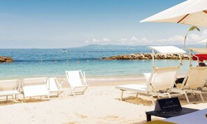 A beach with white lounge chairs and umbrellas, a rocky breakwater, and calm sea. - Luxury 2BR Sanctuary Retreat Overlooking Banderas Bay (Puerto Vallarta)