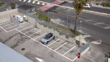 An aerial view of a parking lot with a car, a palm tree, and a road intersection.