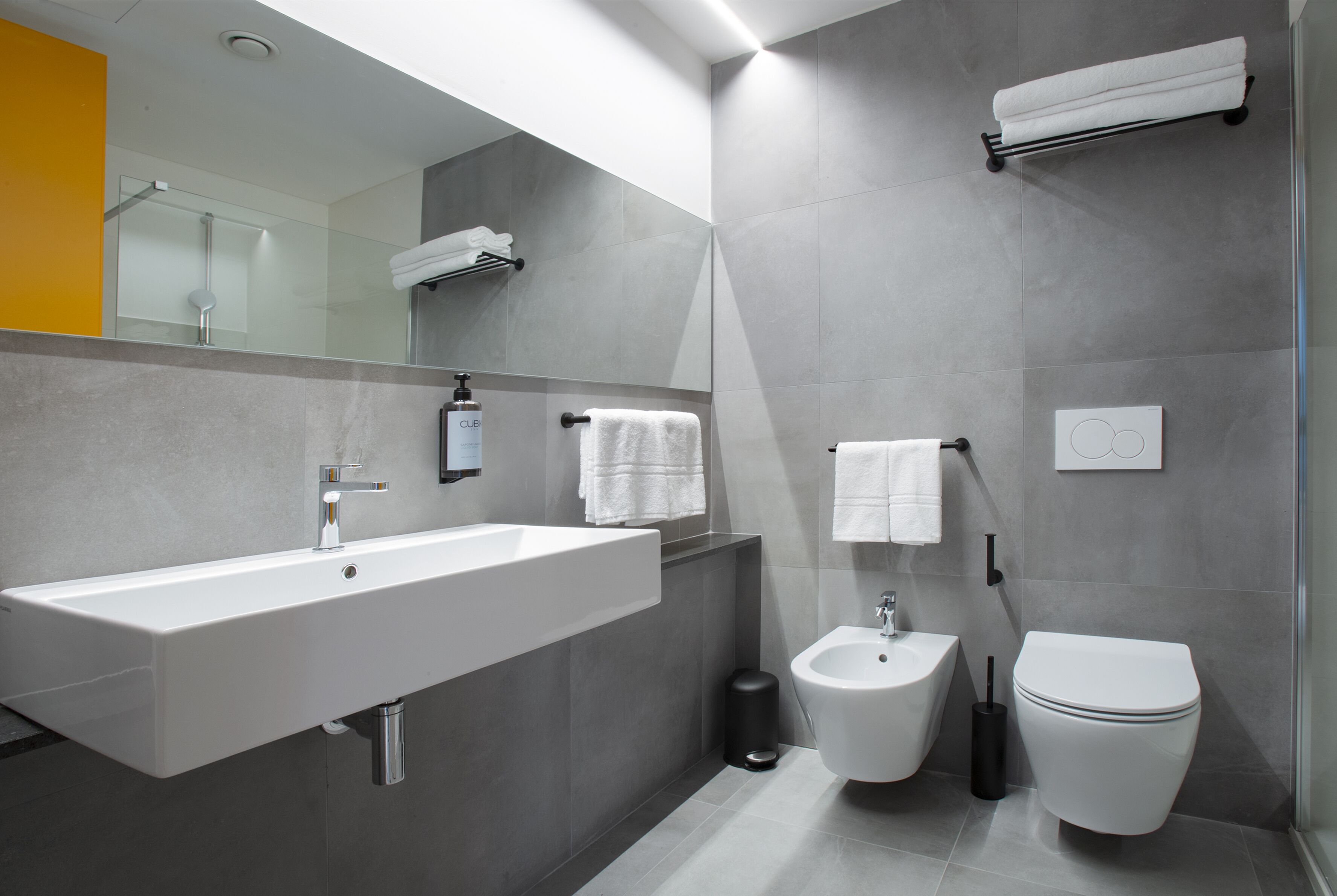 A modern bathroom with a large sink, bidet, and toilet.