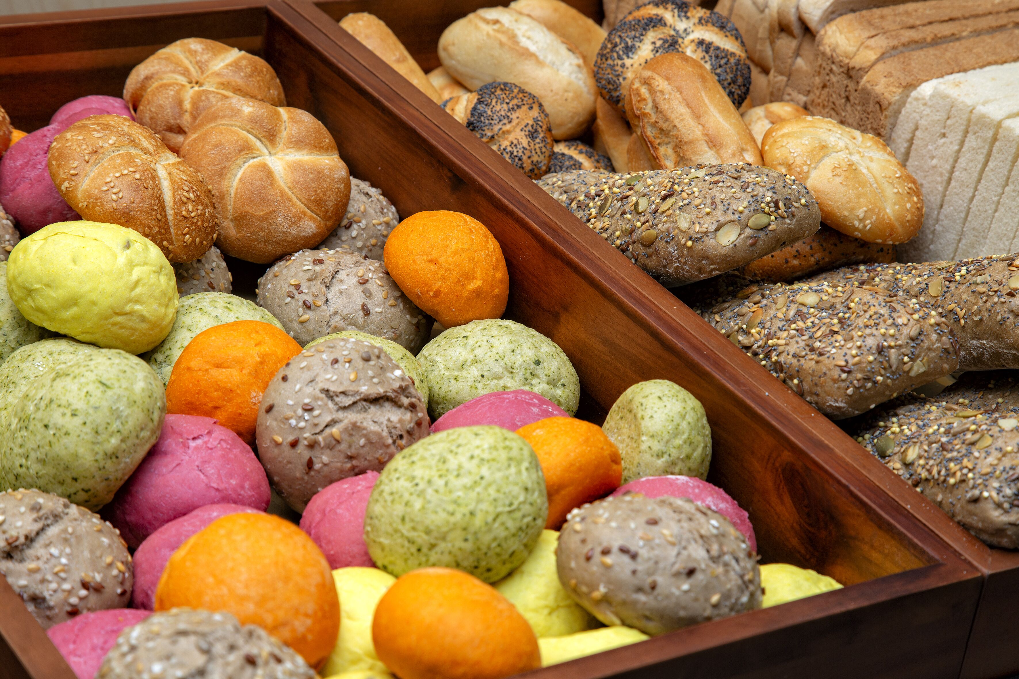 Une variété de pains et de viennoiseries présentés dans une vitrine en bois.