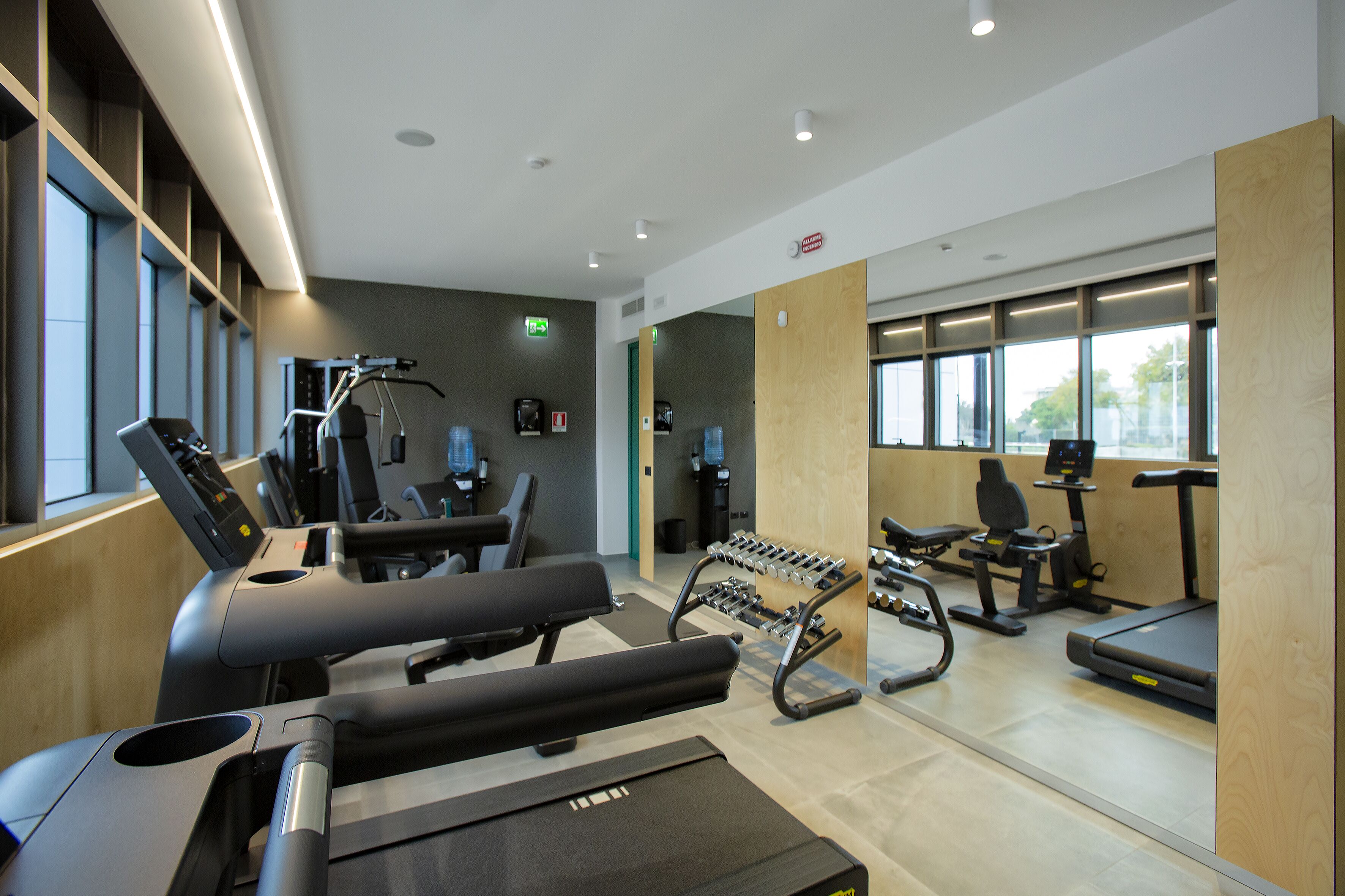 A gym with treadmills, elliptical machines, and weight stations.