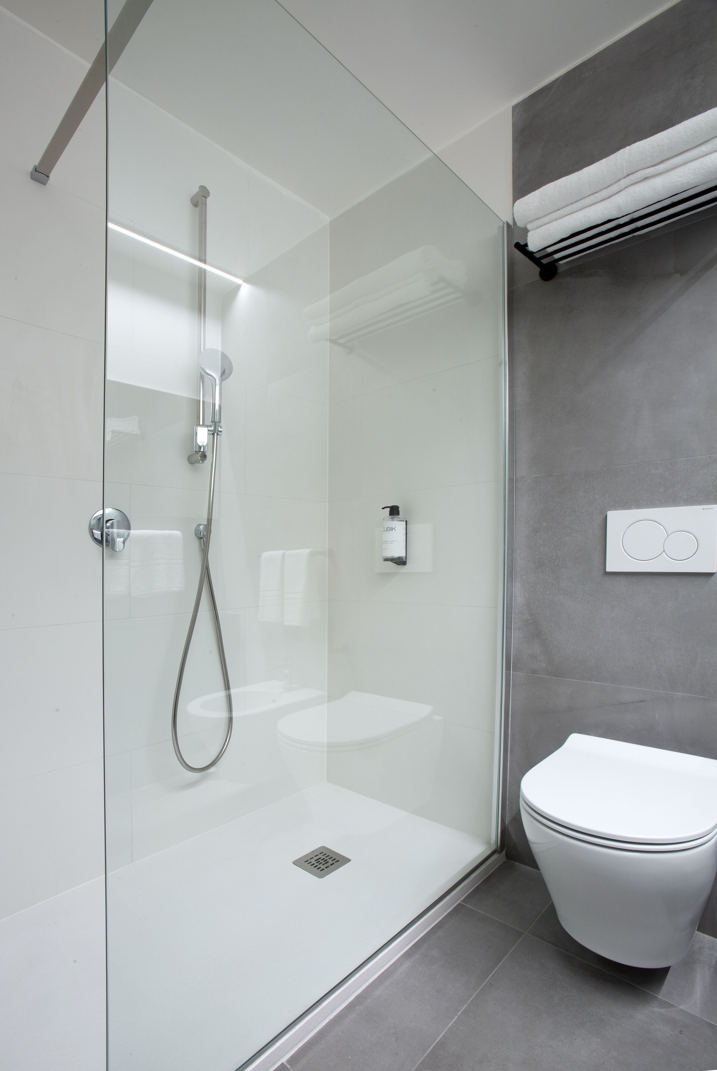 Un bagno moderno con cabina doccia in vetro, un water bianco e un porta asciugamani.