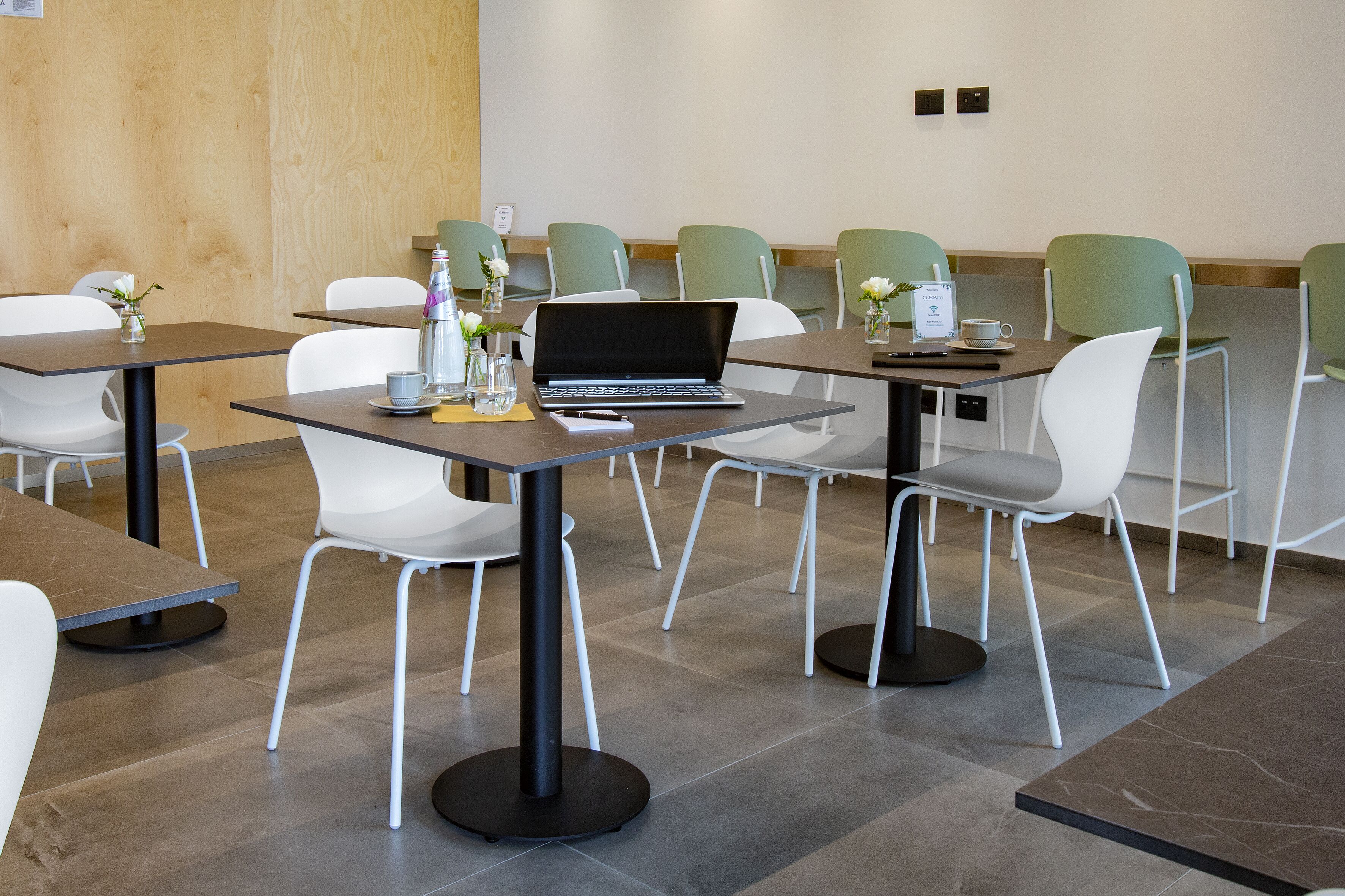 Un salón de conferencias moderno con mesas, sillas y un ordenador portátil.