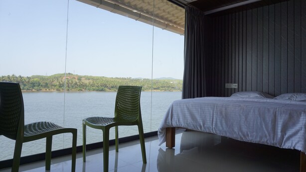 Una habitación con una cama, dos sillas y vistas a un lago.