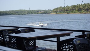 Vista de un lago con un bote a motor a lo lejos, rodeado por un muelle con sillas y mesas.