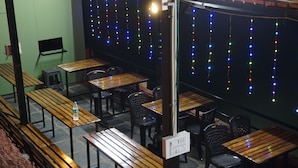 Un restaurante con mesas y sillas de madera, una botella de agua sobre una mesa y luces de colores colgando en la pared.