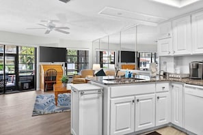 A modern kitchen with white cabinets, a granite countertop, and a built-in oven. - 2BRCondo In Palm Harbor With Pool! (Palm Harbor)