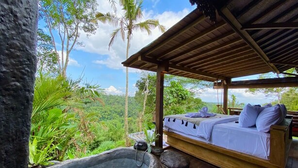 A wooden bed with white linens and pillows, a stone hot tub, and a wooden pergola. - Sunia Jungle Ubud View by EPS (Sebatu)