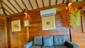 A wooden interior with a sofa, air conditioning unit, and framed artwork. - Sunia Jungle Ubud View by EPS (Sebatu)
