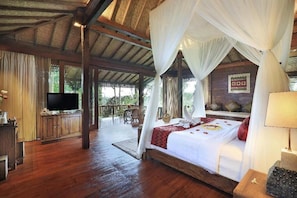 A spacious room with a large bed, a television, and a balcony with a view of the outdoors. - Sunia Jungle Ubud View by EPS (Sebatu)