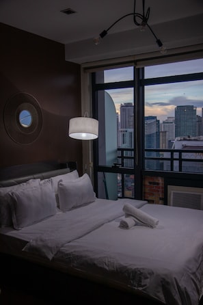 A hotel room with a large bed, a round mirror on the wall, and a view of a cityscape through a large window. - [KStayE]Studio,Best Sunset Pool/Luxury&Hotel Style (Makati)