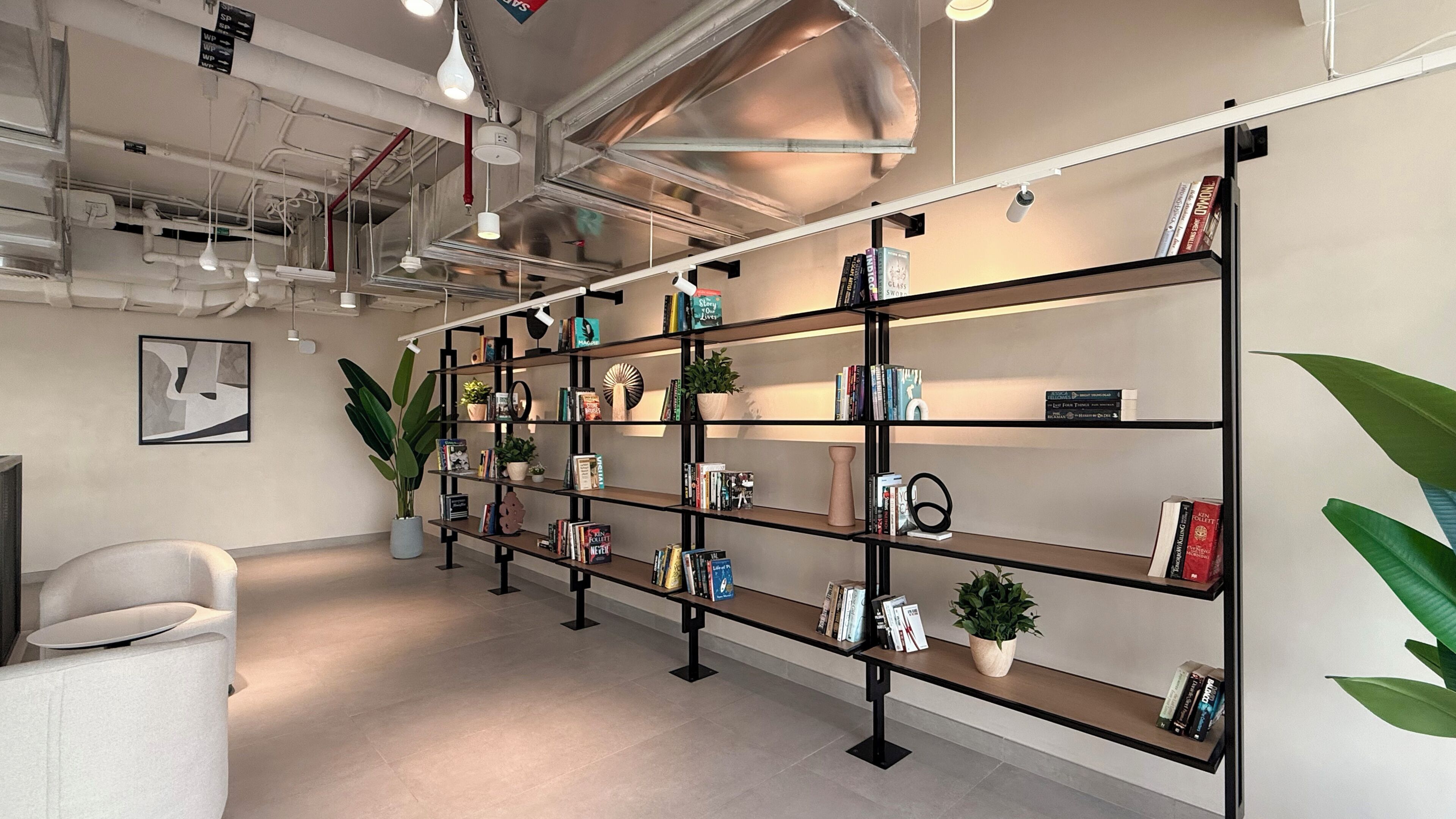 Een moderne bibliotheek met boekenplanken, een potplant en een witte stoel.