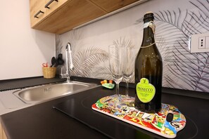 Een aanrecht met een fles prosecco, twee glazen en een kleurrijke onderzetter.