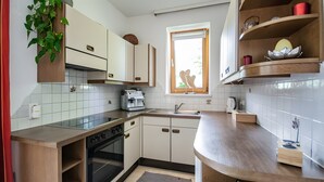 Een moderne keuken met witte kasten, een inbouwoven, een koffiezetapparaat en een raam met uitzicht.