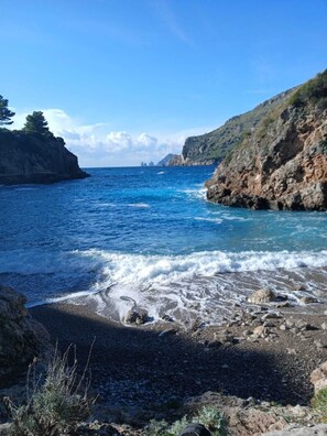 A coastal landscape with rocky terrain, clear blue sea, and distant landforms. - Rosa Haus - A House in the Picturesque Countryside of Nerano (Campania)