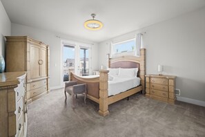 A bedroom with a large bed, wooden dresser, and a desk with a chair.
