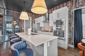 Eine moderne Küche mit Kochinsel, Barhocker und einer fliesenverzierten Spritzschutzwand.