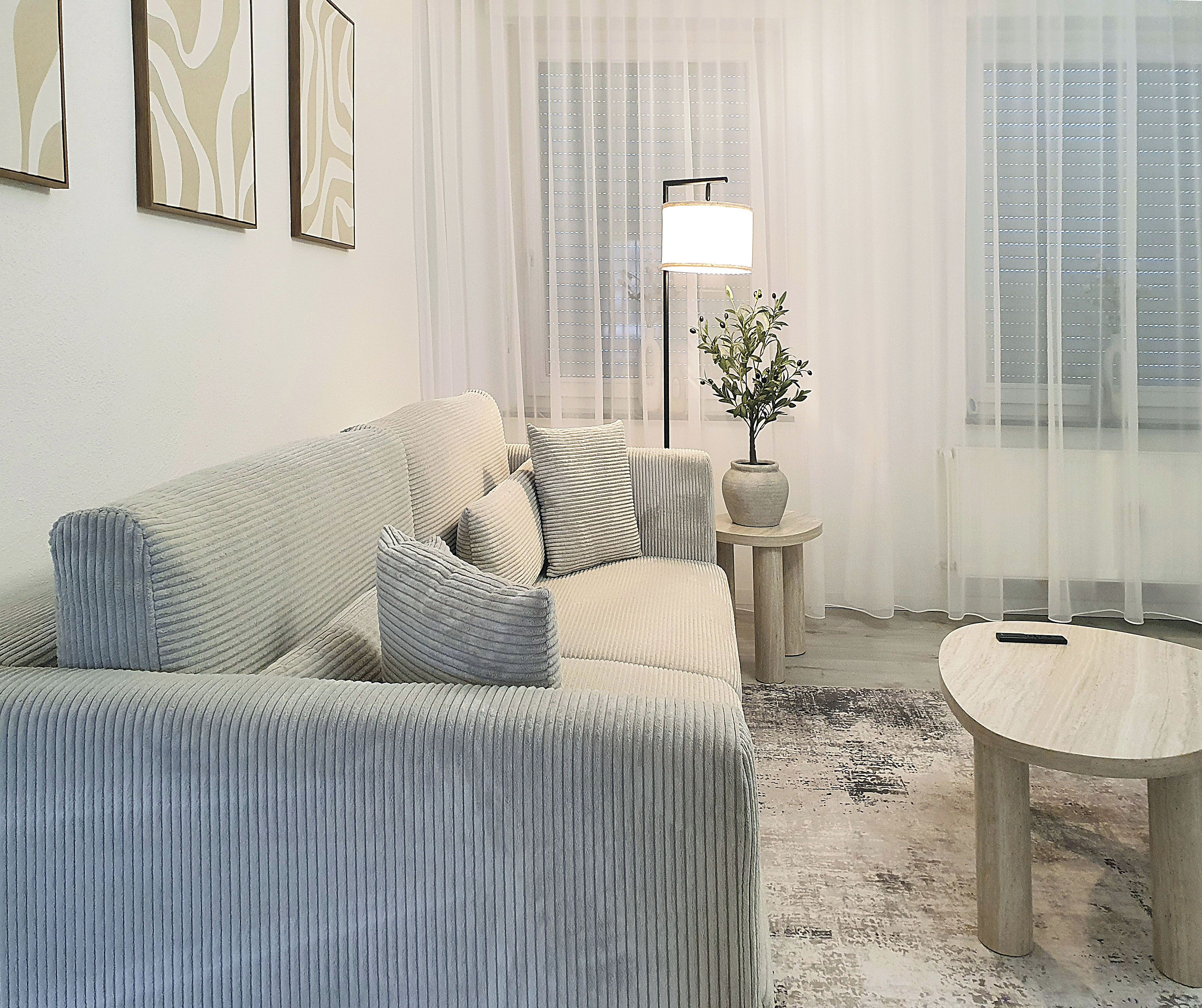 A living room with a sofa, a small table, a lamp, and a potted plant.