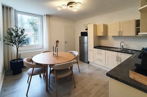 Eine moderne Küche mit Esstisch, Schränken und einem Kühlschrank.