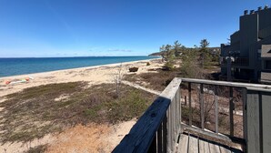Une vue sur la plage avec une terrasse en bois, une plage de sable et un bâtiment doté de balcons.