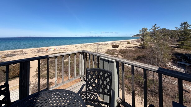 Une terrasse en bois avec une table et des chaises donnant sur une plage.