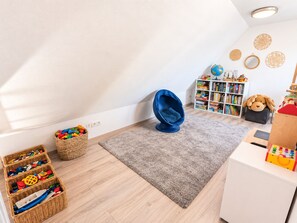 A child's playroom with a blue egg chair, a bookshelf, and a toy storage area. - "Meer" Vacation Rental - with a terrace and garden (Butjadingen)