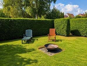 A well-maintained lawn with two lounge chairs and a metal bowl, surrounded by neatly trimmed hedges and trees. - "Meer" Vacation Rental - with a terrace and garden (Butjadingen)