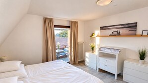 Una camera da letto con un letto, una scrivania, una sedia, un termosifone e una finestra con tende.
