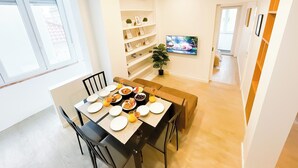Ein Essbereich mit einem Tisch für vier Personen, einem Blumentopf und einem Fernseher an der Wand.