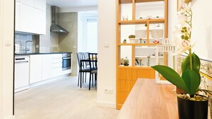 Eine moderne Küche mit weißen Schränken, einem eingebauten Ofen und einem Essbereich mit einem Holztisch und Stühlen.