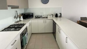 A modern kitchen with white cabinets, a gas stove, a microwave, and a sink. - Bay & wetland views in beautiful Williamstown, Relax, unwind and enjoy (Williamstown)