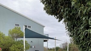 A gravel pathway leading to a building with a blue exterior and a covered outdoor seating area. - Bay & wetland views in beautiful Williamstown, Relax, unwind and enjoy (Williamstown)