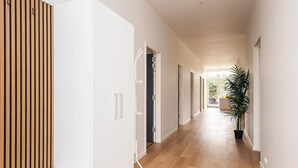 Um corredor moderno com lambris de madeira, portas brancas e um vaso com planta.