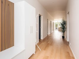 A modern hallway with wooden paneling, white doors, and a potted plant.