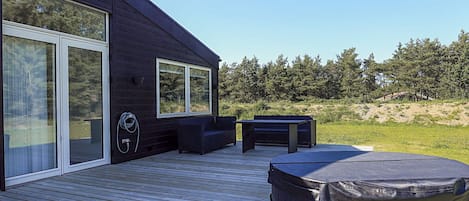 Una terraza de madera con mobiliario exterior y un jacuzzi.