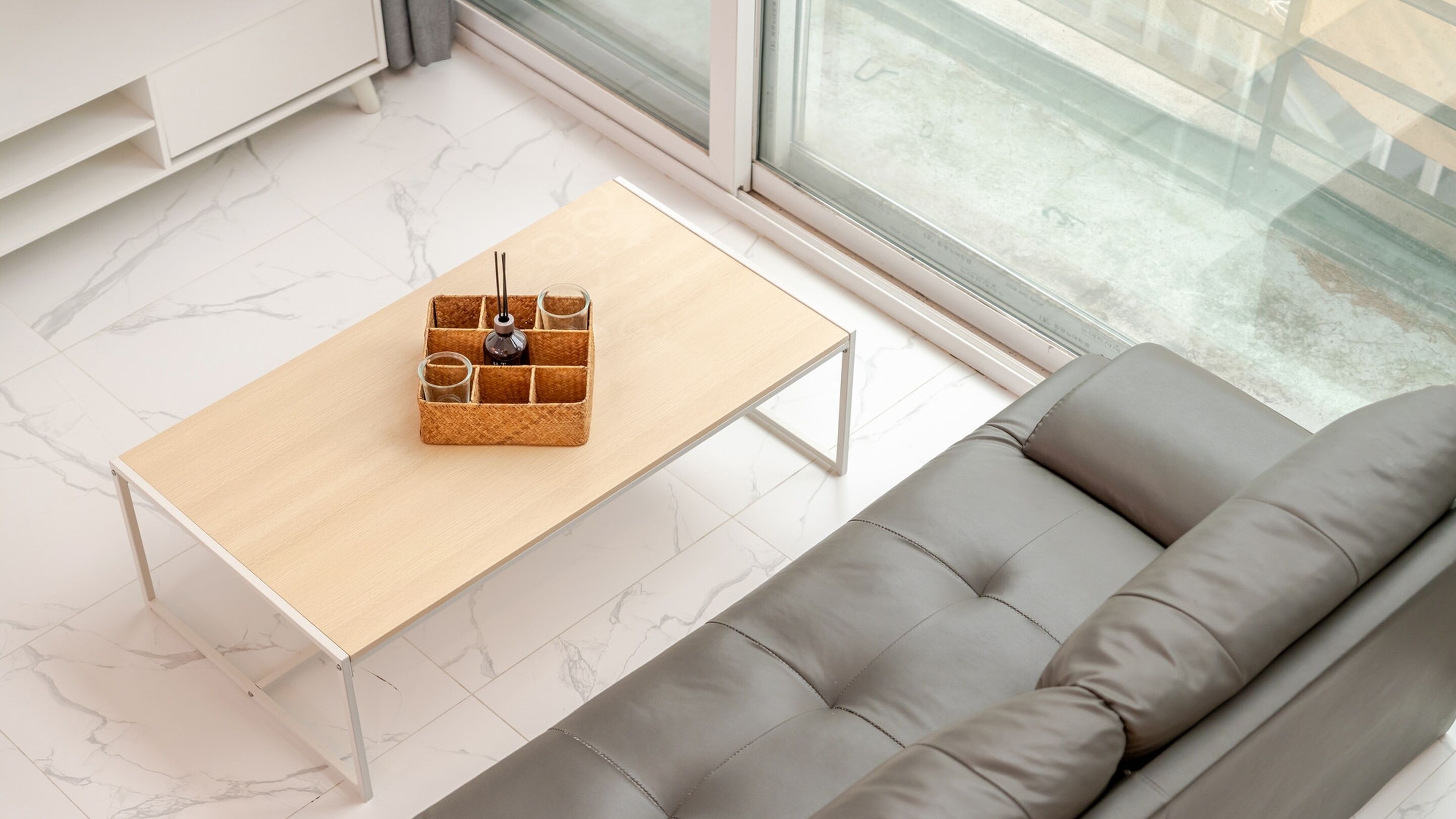 Una sala de estar moderna con una mesa de centro de madera, un sofá gris y un ventanal grande.