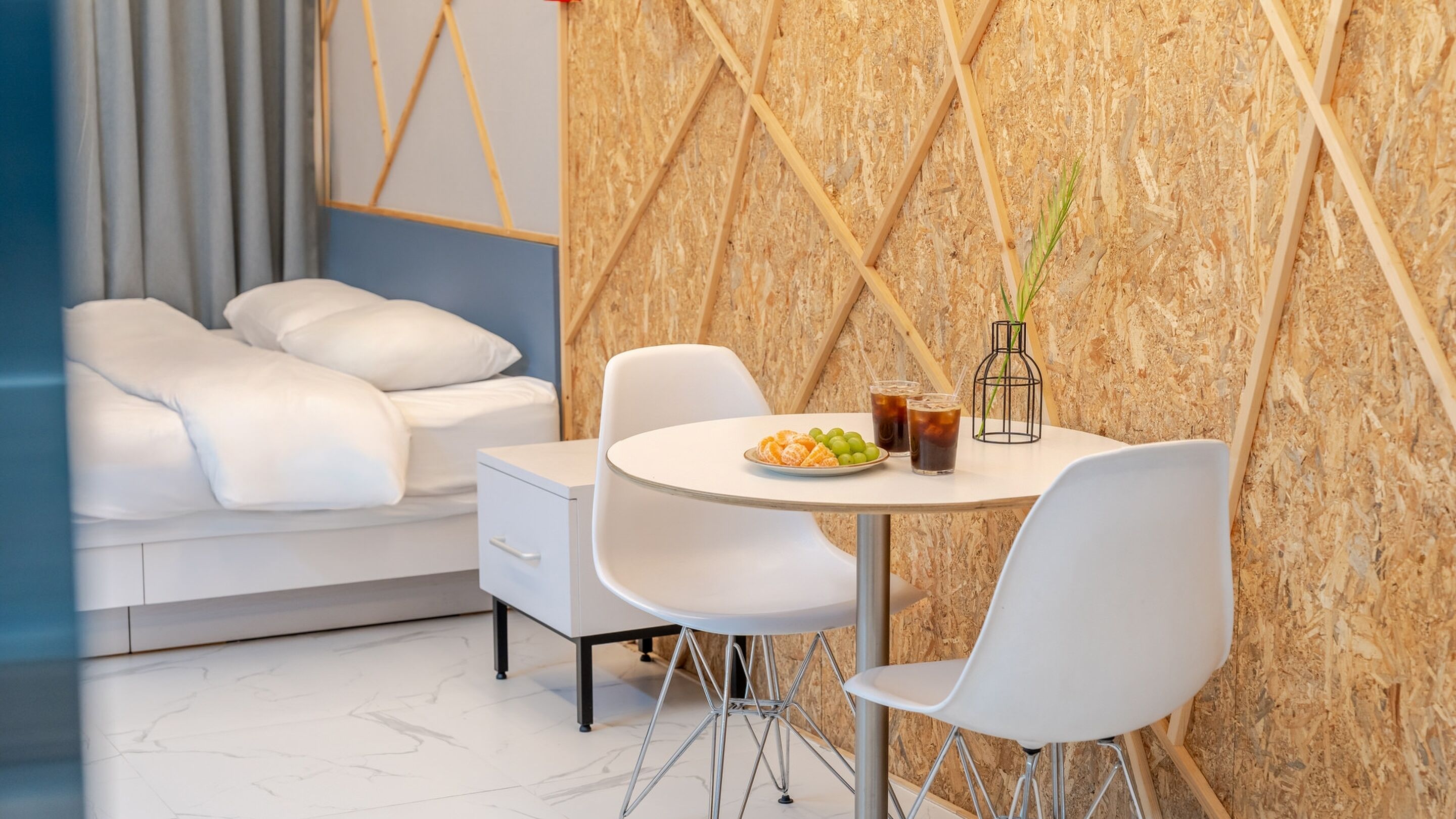 A modern room with a white sofa, a dining table with chairs, and a wall with a geometric pattern.