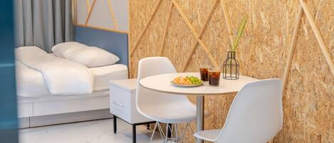 A modern room with a white sofa, a dining table with chairs, and a wall with a geometric pattern.