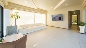 A modern living room with a sofa, a dining table with chairs, a potted plant, and a painting on the wall. - Taean Sagye Pension (Taean)