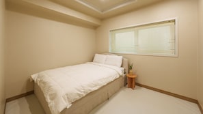 A bedroom with a bed, a window with blinds, a small wooden side table with a plant, and a ceiling light. - Taean Sagye Pension (Taean)